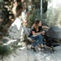 Parent pushing a lightweight compact travel stroller with a newborn baby outdoors