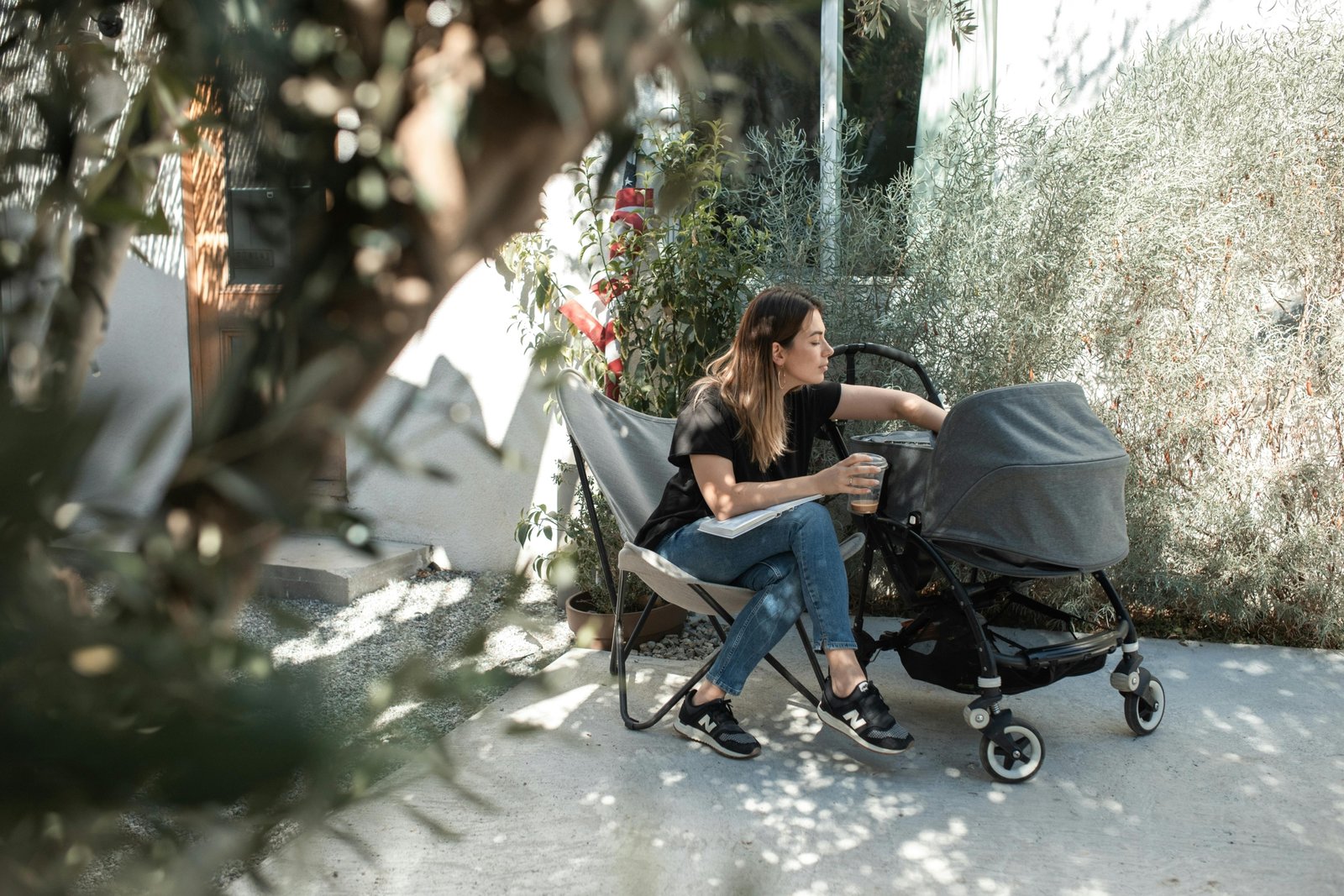 Parent pushing a lightweight compact travel stroller with a newborn baby outdoors