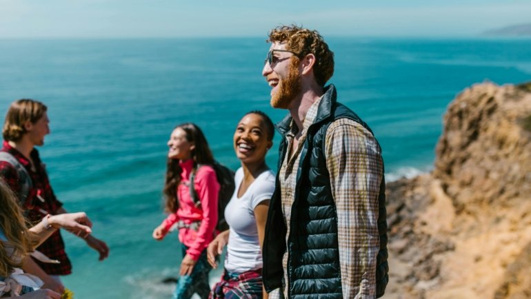 Group of joyful travelers laughing outdoors enjoying funny moments during their trip
