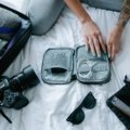 Woman packing travel accessories including organizer bags, compression cubes, and crossbody bag for a comfortable and stylish trip