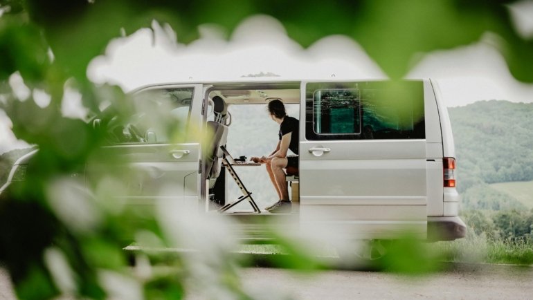 remote worker using laptop inside camper van illustrating flexible cross country travel job lifestyle