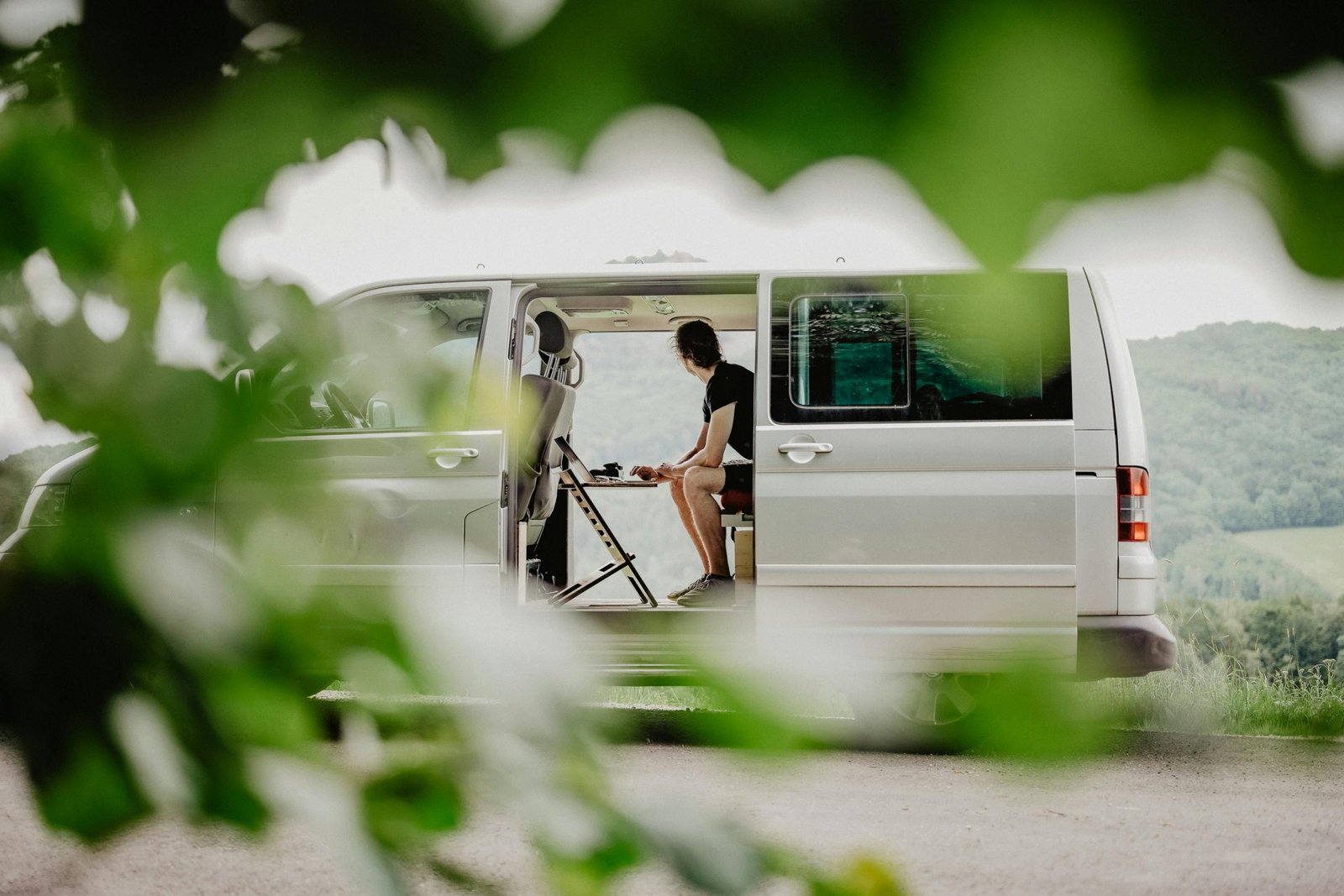 remote worker using laptop inside camper van illustrating flexible cross country travel job lifestyle
