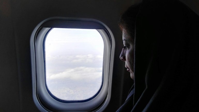Muslim passenger praying on airplane for safety and spiritual protection during flight