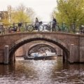 Travelers biking along Amsterdam canals enjoying personalized Netherlands tour and local cultural experience