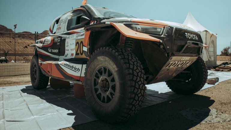 Toyota Tacoma equipped with long travel suspension kit driving over rocky off-road trail