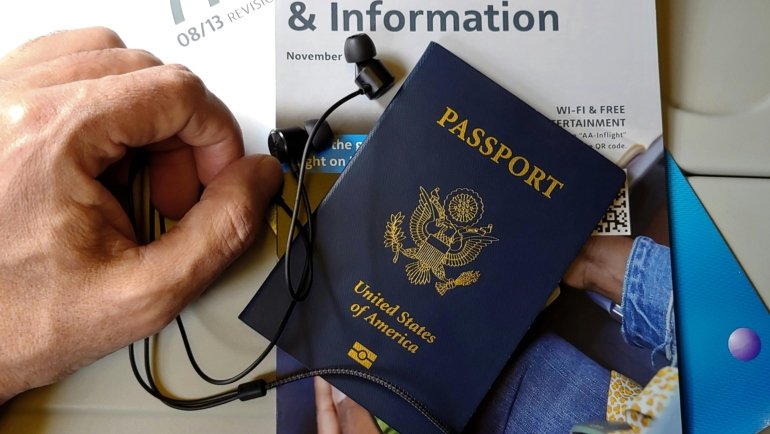 Wired noise cancelling earbuds in use by traveler on airplane for noise reduction and comfort during flight