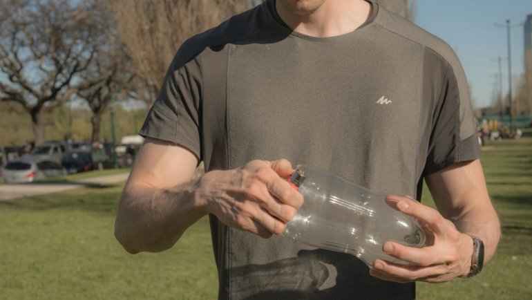 Man using a portable travel urinal outdoors during a hiking trip for convenience and hygiene