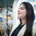 Young woman holding a compact travel perfume bottle, embodying modern and bold travel fragrance inspired by Billie Eilish