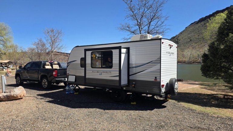 Lightweight 3500 lb travel trailer parked at scenic campsite with family enjoying outdoor camping experience