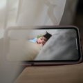 Parent using portable travel baby monitor to safely watch sleeping baby during a trip