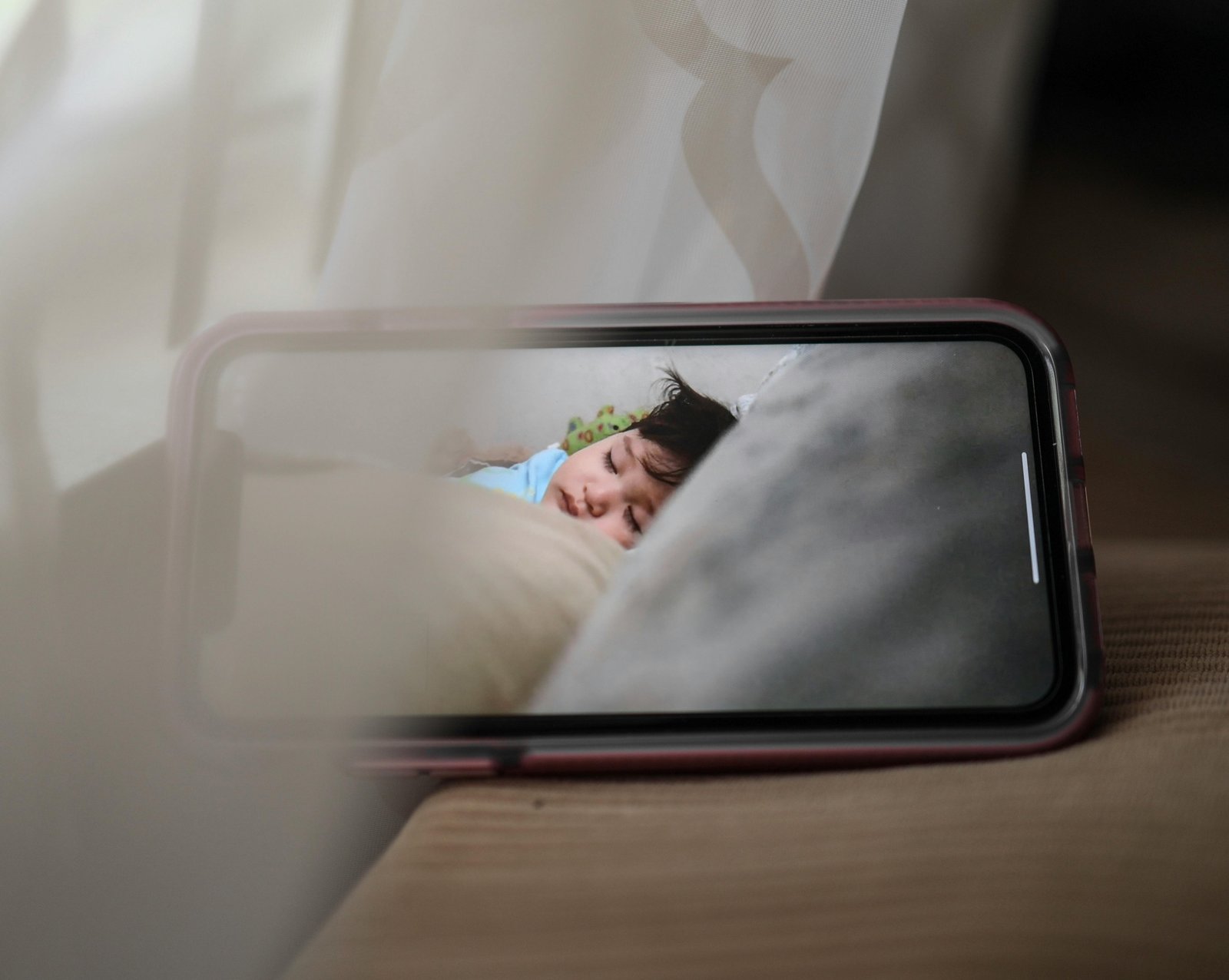 Parent using portable travel baby monitor to safely watch sleeping baby during a trip