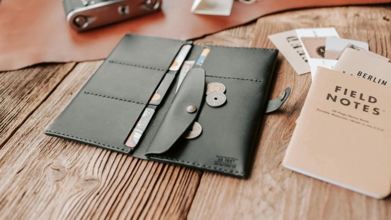 Open travel billfold showing RFID-blocking compartments with passport, credit cards, and cash organized for safe and convenient travel