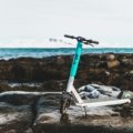 Foldable travel scooter folded and ready to carry in a bright outdoor travel environment