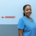 Smiling travel nurse with suitcase outside hospital representing American Mobile travel nursing flexibility and opportunities