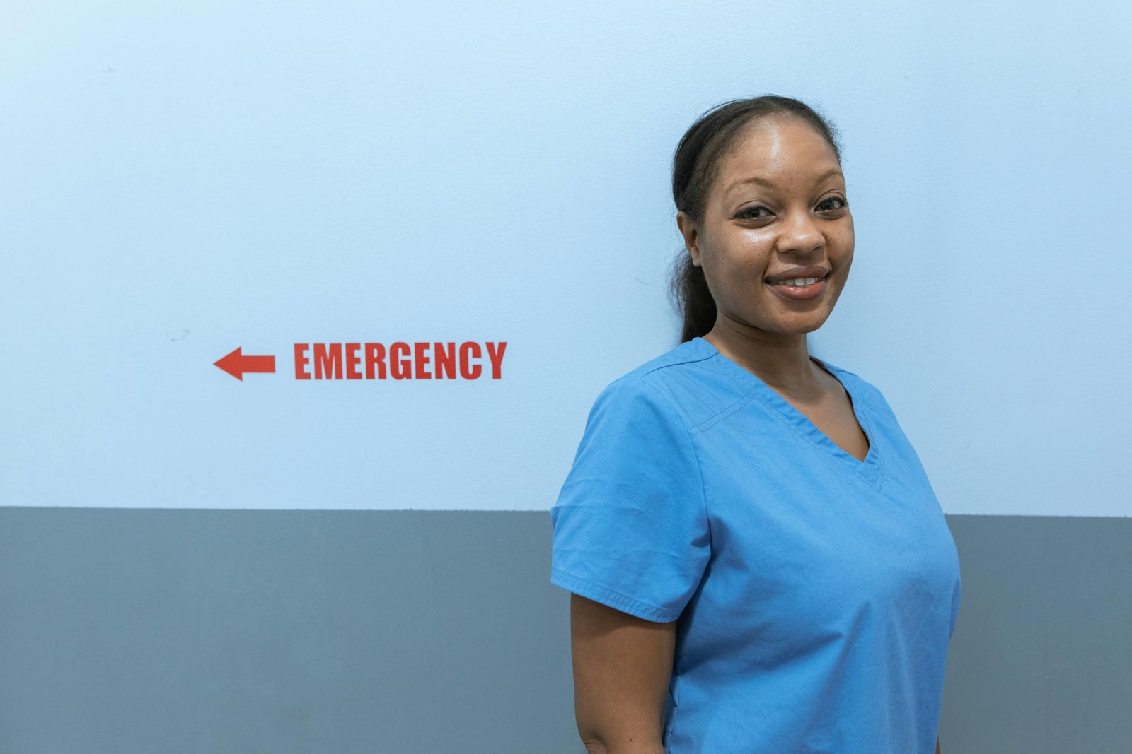 Smiling travel nurse with suitcase outside hospital representing American Mobile travel nursing flexibility and opportunities