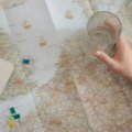 Happy traveler using laptop and map to plan a personalized trip with travel agency assistance in Boston