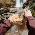 Traveler enjoying a hot meal from a portable food warmer outdoors during a trip