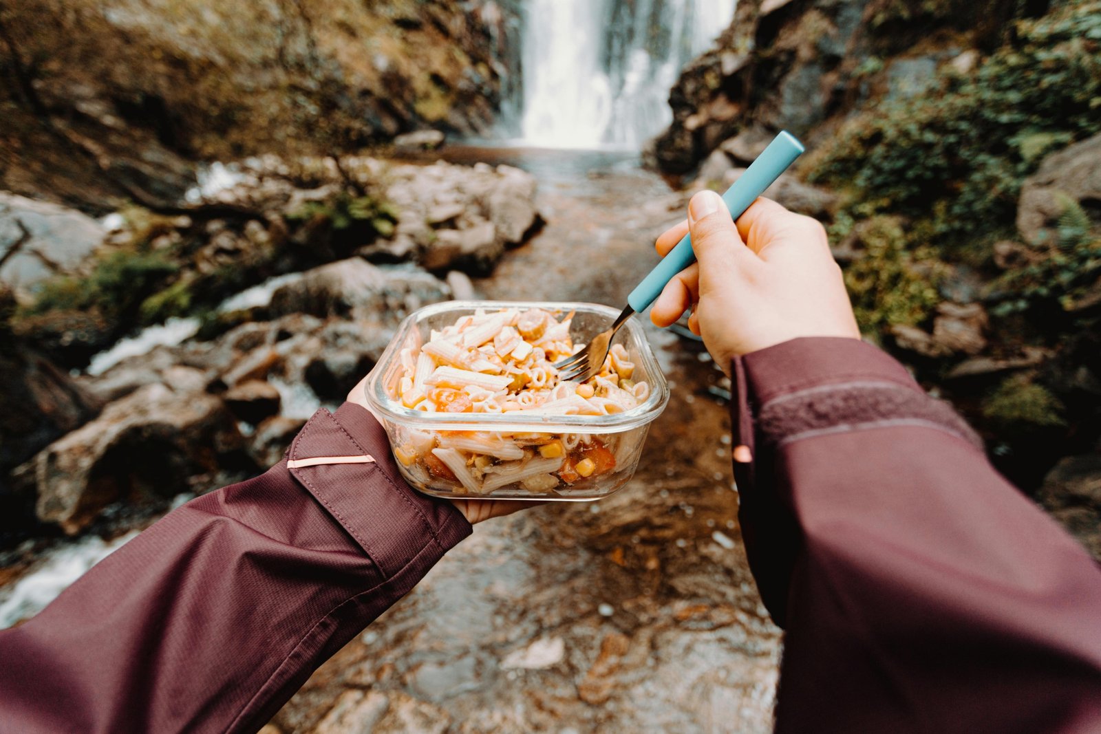 Traveler enjoying a hot meal from a portable food warmer outdoors during a trip