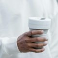 Compact collapsible travel cup used outdoors by a traveler for eco-friendly hydration on the go