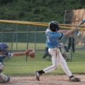Young baseball player swinging a lightweight travel ball bat during a competitive youth game