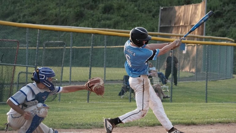 Young baseball player swinging a lightweight travel ball bat during a competitive youth game