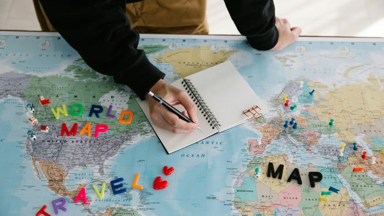Travel planning notebook with laptop and map illustrating organized trip preparation