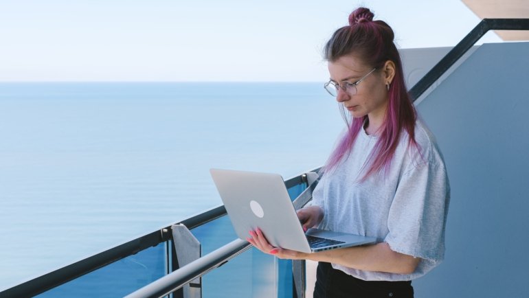 Digital nomad working remotely on a laptop from a scenic beach location, showcasing the freedom of remote jobs for travelers in 2026