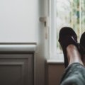 Woman wearing comfortable and stylish travel slippers relaxing in a hotel room during a trip