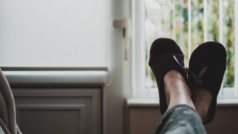 Woman wearing comfortable and stylish travel slippers relaxing in a hotel room during a trip