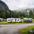 Lightweight rpod travel trailer parked at a picturesque campsite with mountains and forest background