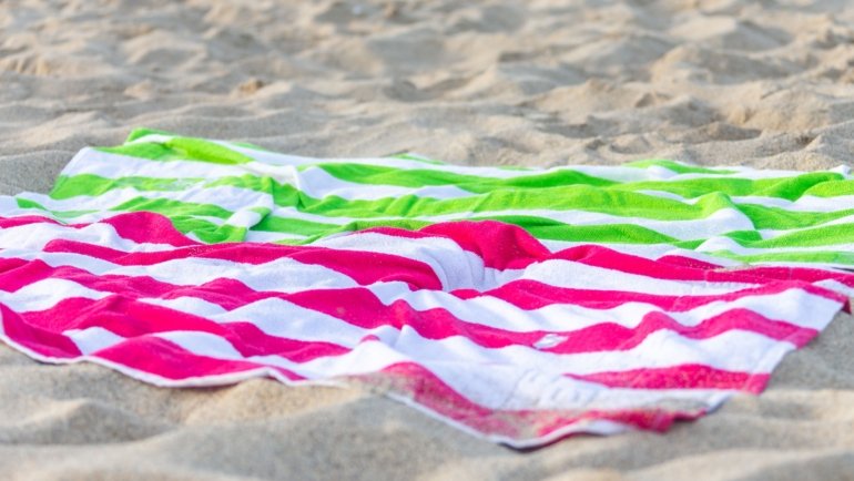 Lightweight colorful travel beach towel on sandy beach with ocean view, perfect for quick-dry and sand-resistant use