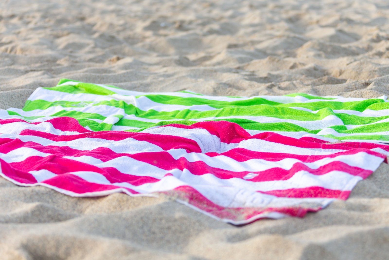 Lightweight colorful travel beach towel on sandy beach with ocean view, perfect for quick-dry and sand-resistant use
