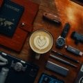 Flat lay of essential travel gadgets and accessories including portable charger, travel pillow, noise-cancelling headphones, and travel journal