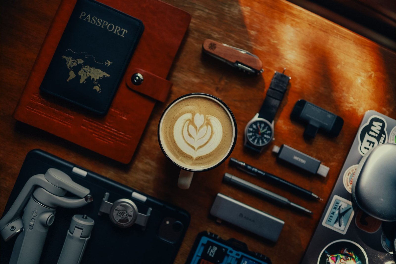 Flat lay of essential travel gadgets and accessories including portable charger, travel pillow, noise-cancelling headphones, and travel journal