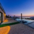Luxury private villa at sunset with serene outdoor seating overlooking a pristine landscape, perfect for exclusive travel experiences