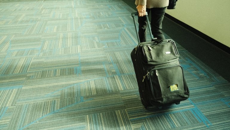 Traveler carrying a lightweight strap travel bag over shoulder walking through airport terminal