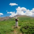 Travel nurse with medical gear in front of Colorado mountain landscape showcasing healthcare career and outdoor lifestyle