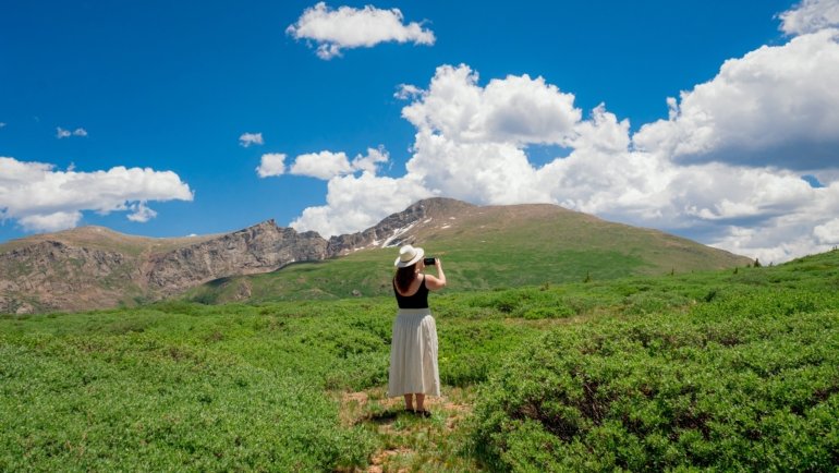 Travel nurse with medical gear in front of Colorado mountain landscape showcasing healthcare career and outdoor lifestyle