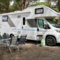 Outdoor RV travel trailer parked in nature with camping setup, showcasing comfort and adventure