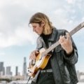 Lightweight travel electric bass guitar being played outdoors, highlighting portability and musical freedom for touring musicians