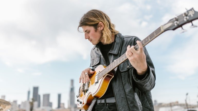 Lightweight travel electric bass guitar being played outdoors, highlighting portability and musical freedom for touring musicians