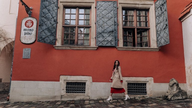 Stylish woman in comfortable dress walking on European street during travel