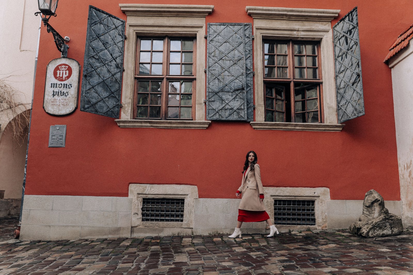 Stylish woman in comfortable dress walking on European street during travel