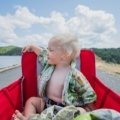 Toddler sitting on a compact travel potty outdoors during family travel, demonstrating portability and comfort