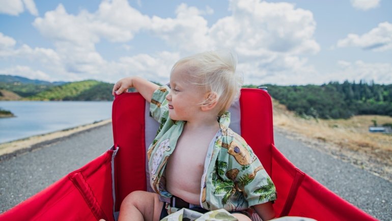 Toddler sitting on a compact travel potty outdoors during family travel, demonstrating portability and comfort
