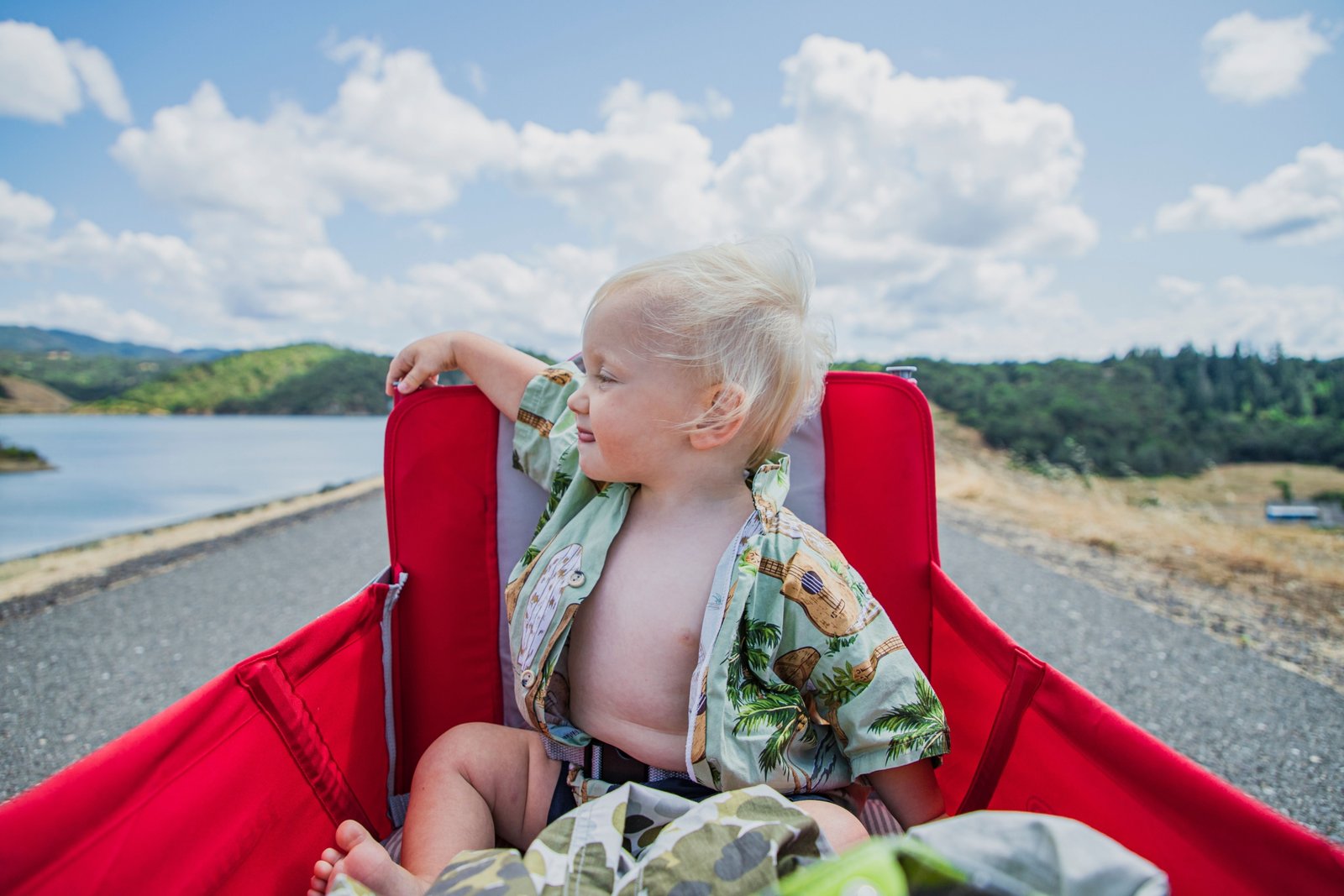 Toddler sitting on a compact travel potty outdoors during family travel, demonstrating portability and comfort