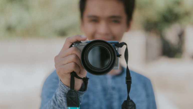 Traveler using a compact mirrorless camera to capture high-quality photos during a scenic outdoor adventure