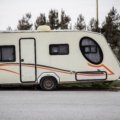Toy hauler travel trailer with open garage and recreational vehicles parked in nature