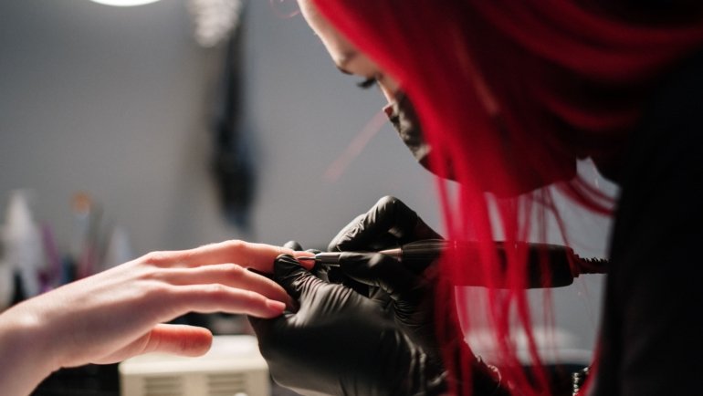 Mobile nail technician giving a professional manicure in a home setting, showcasing convenient and personalized nail care services