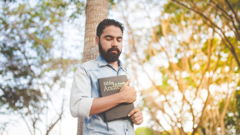 Traveler holding a Bible outdoors symbolizing spiritual protection and peace during travel